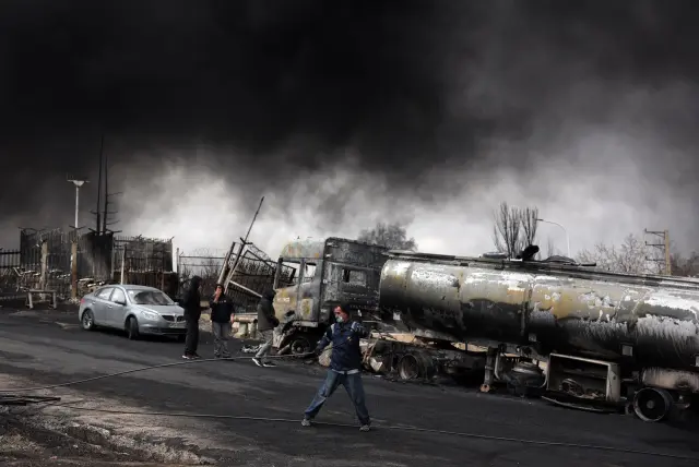 Varios trabajadores observan una nube tóxica de humo en la refinería de petróleo de Shahran tras el ataque aéreo en Teherán, Irán.