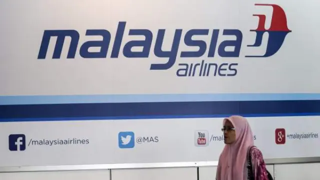 Una pasajera pasa junto a un cartel publicitario de la aerolínea Malaysia Airlines en el Aeropuerto Internacional de Kuala Lumpur en Sepang (Malasia).