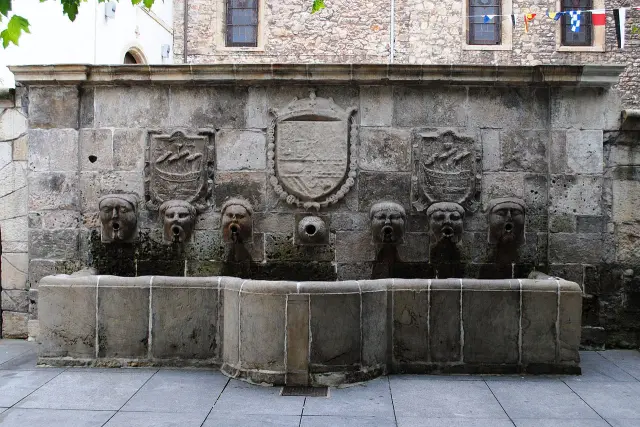 Situada en pleno casco antiguo de Avilés (Asturias), entre el palacio de Ferrera y la iglesia de San Nicolás de Bari, esta original fuente, del siglo XVII, está formada por un frontal del que surgen seis cabezas humanas de cuyas bocas brota el agua, que cae en un pilón rectangular, pero ovalado en el centro, que en sus tiempos servía de abrevadero para el ganado.