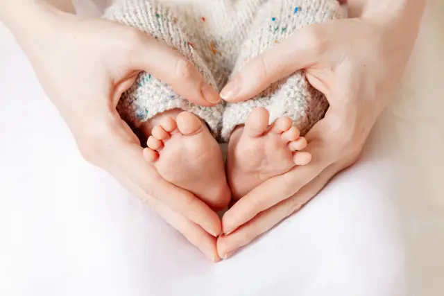 Las manos de una madre con los pies de un bebé.