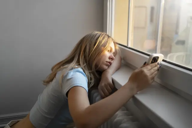 Foto de archivo de una adolescente mirando el teléfono móvil.