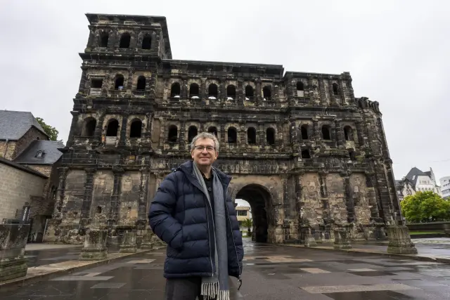 Tréveris (Alemania), 19/10/2025.- Santiago Posteguillo, delante de la Porta Nigra durante el viaje de presentación de su nueva novela sobre Julio César, 'Los tres mundos' (Ediciones B), en la que narra cómo el político y militar romano "forjó" un Occidente que ahora ve "en decadencia". EFE/Ediciones B. -SOLO USO EDITORIAL/SOLO DISPONIBLE PARA ILUSTRAR LA NOTICIA QUE ACOMPAÑA (CRÉDITO OBLIGATORIO)-
