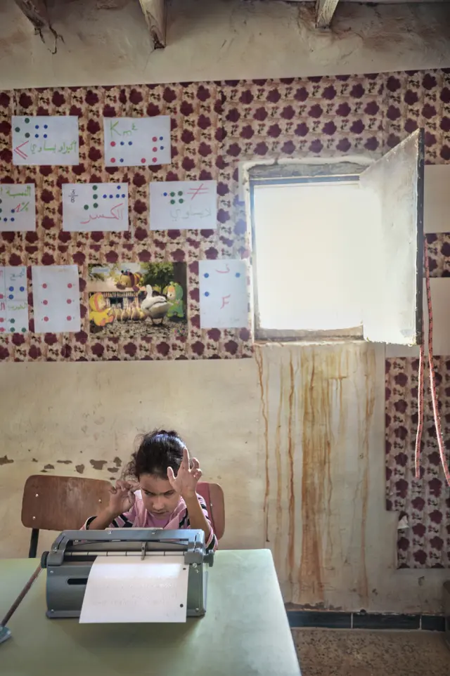 Farida, ciega de ocho años, práctica con una maquina de escribir.