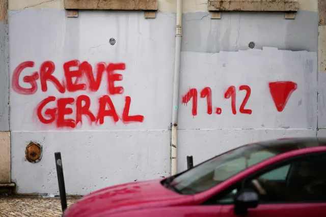 A car drives past a graffiti reading in Portuguese "General Strike", called by workers unions for Dec. 11 to protest against a new labor package announced by the center-right government, in Lisbon, Tuesday, Dec. 9, 2025. (AP Photo/Armando Franca)