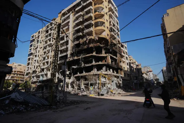 People take photos of a building damaged by an Israeli airstrike in Dahiyeh, Beirut's southern suburbs, Lebanon, Tuesday, March 17, 2026. (AP Photo/Hassan Ammar)