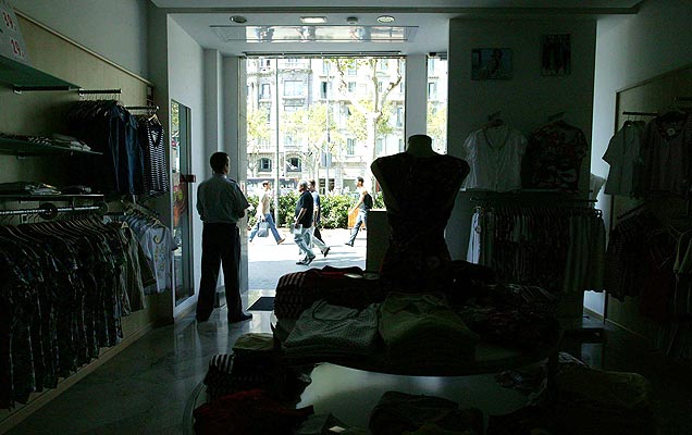 Un empleado de seguridad vigila una tienda sin luz en Barcelona durante el apagón.