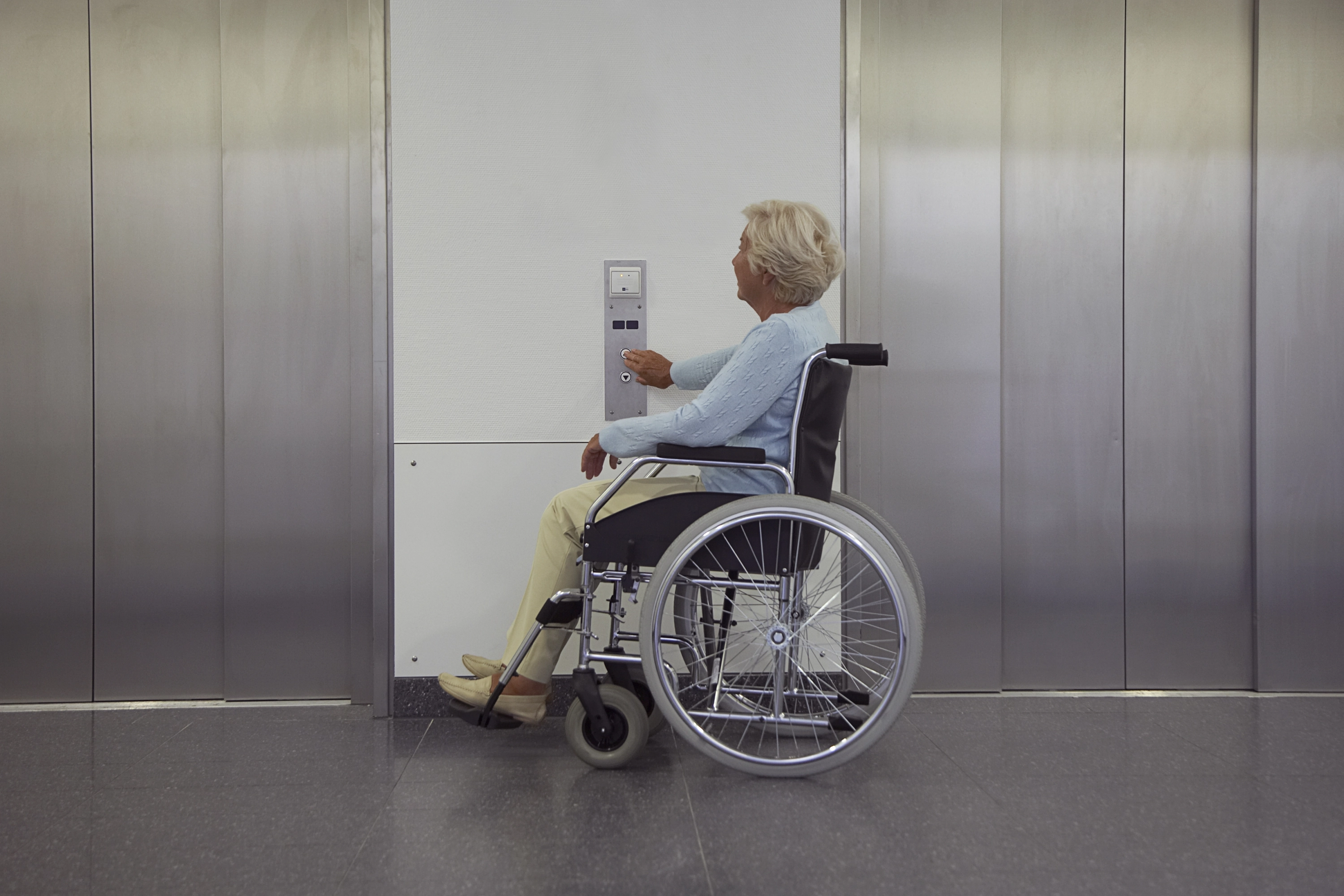 Uma mulher na cadeira de rodas está se preparando para pegar o elevador.