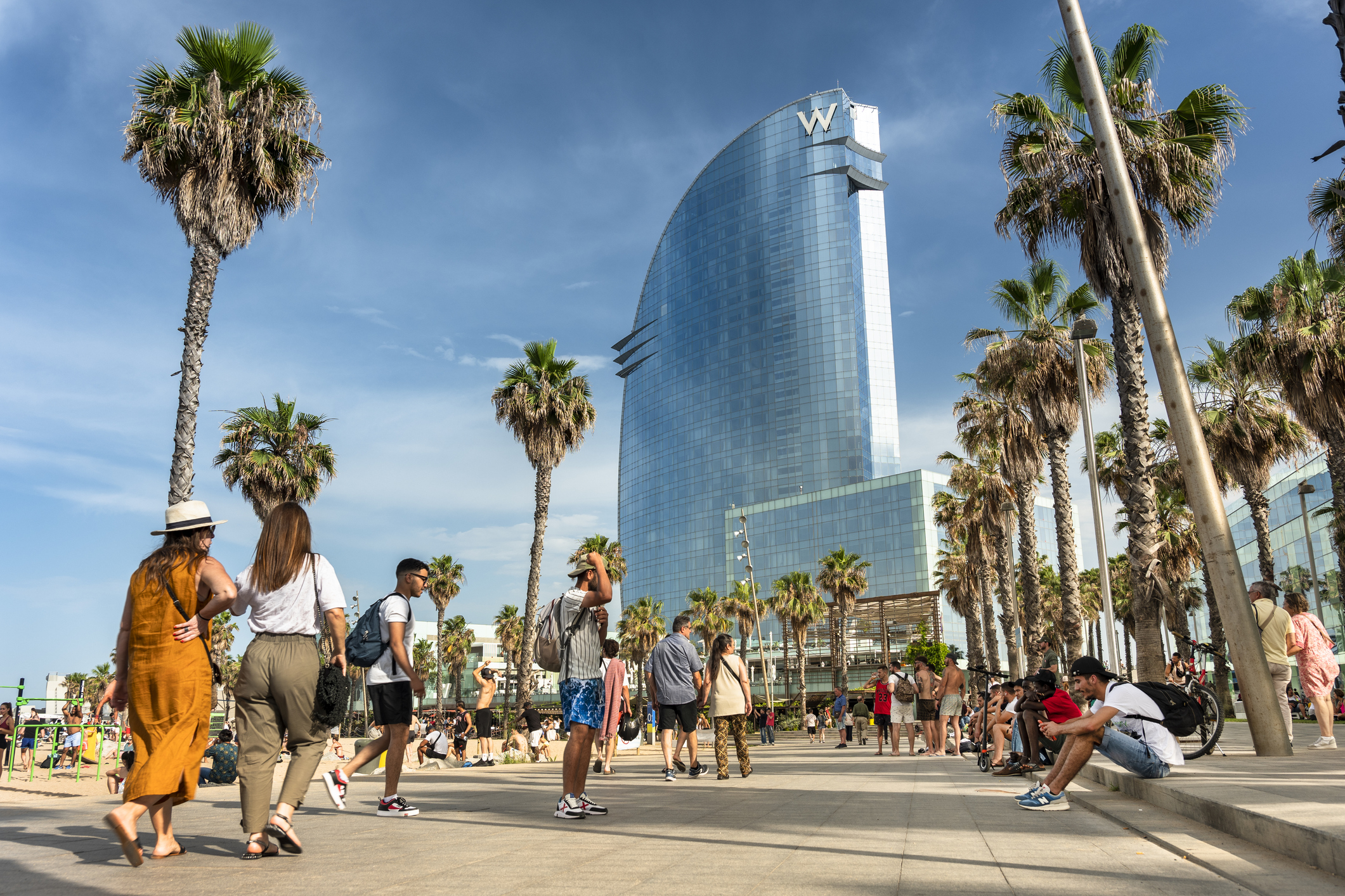 Una multitud de personas caminan por el paseo marítimo de la playa de la Barceloneta en Barcelona.