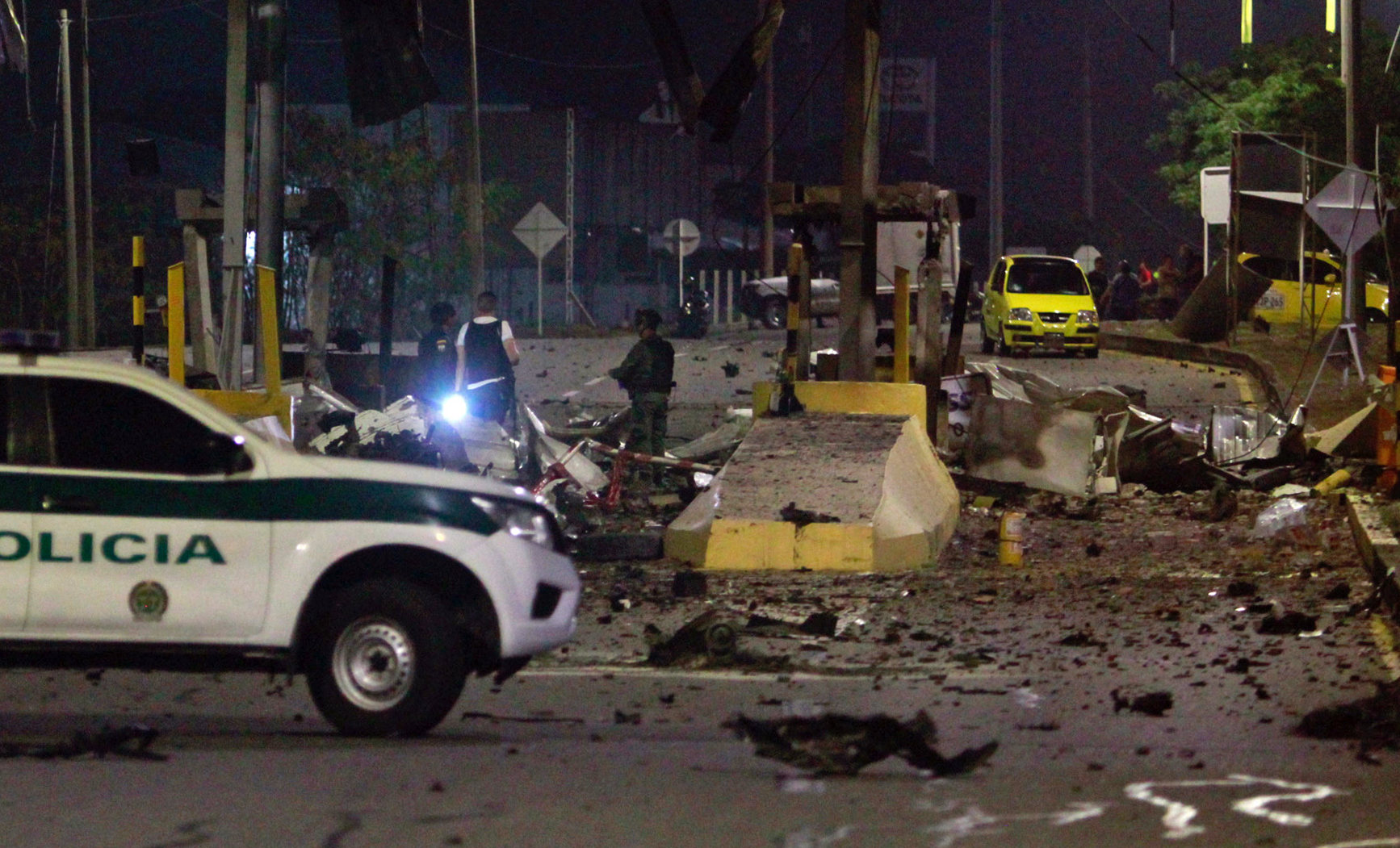 Policías inspeccionan el peaje de Villa del Rosario destruido por explosivos este jueves en Cúcuta, Colombia.