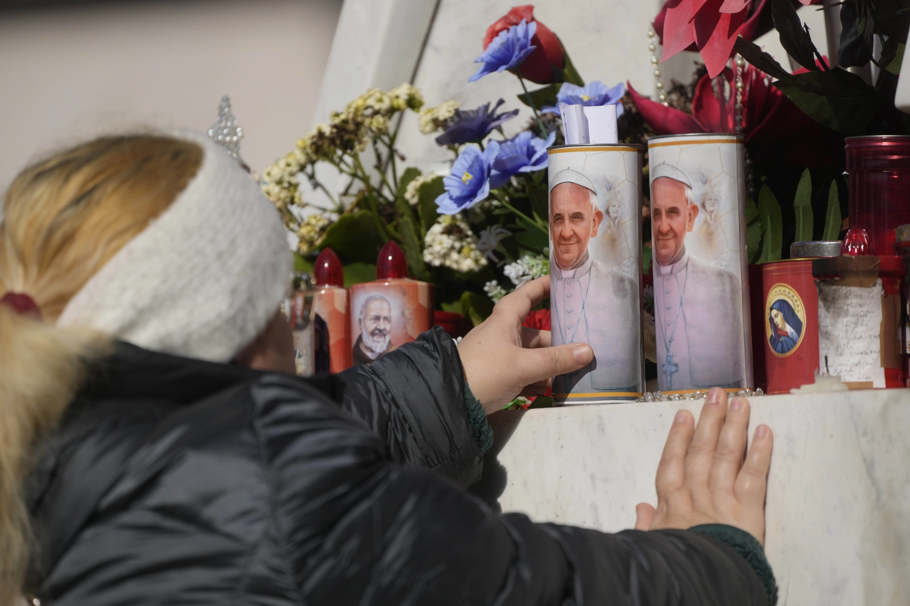 Una mujer lleva velas al altar en honor al papa Francisco en el hospital Gemelli.