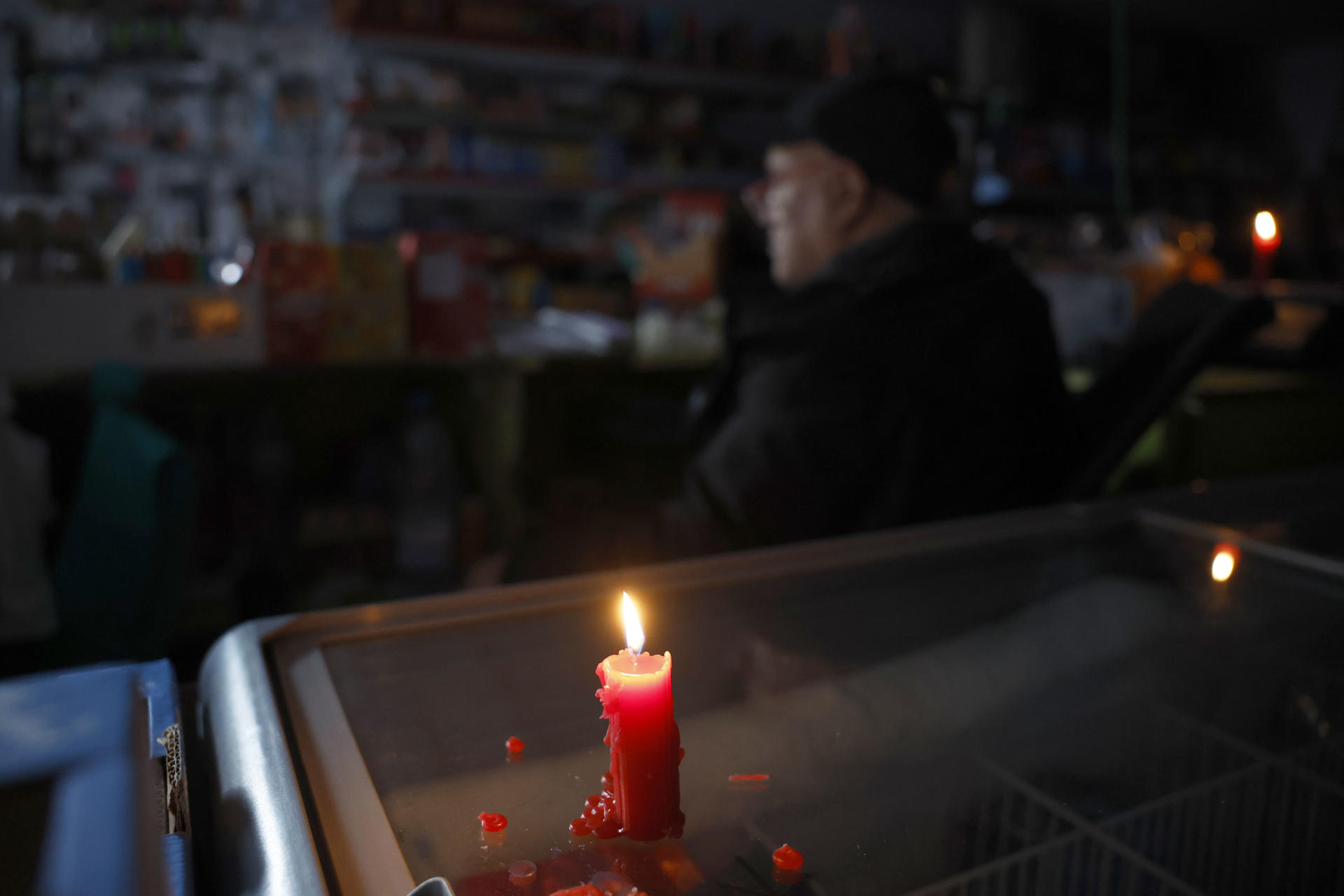 El trabajador de un supermercado se ilumina con una vela durante el apagón eléctrico, en Barcelona.