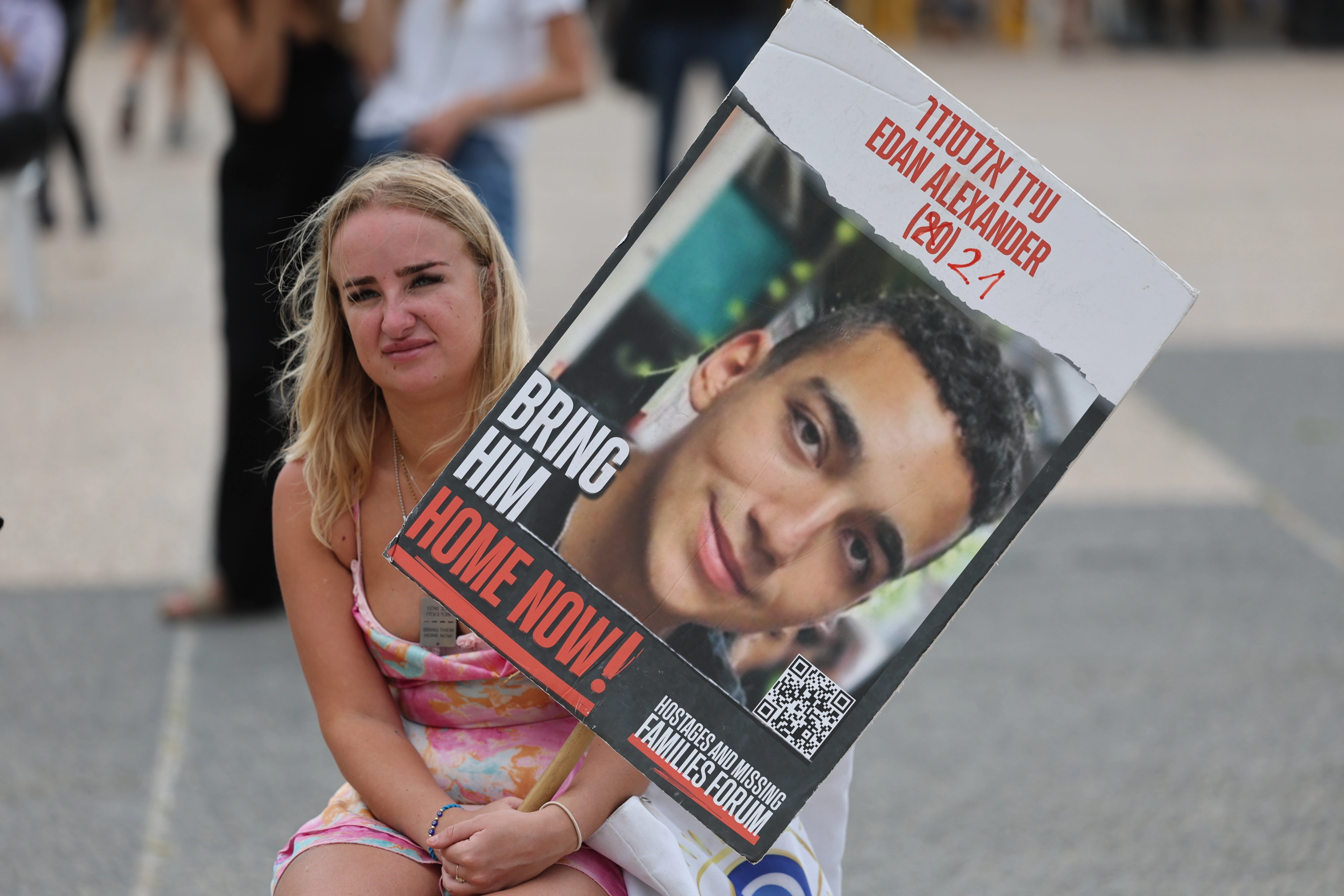 Una mujer sostiene una pancarta con la imagen de Edan Alexander, el estadounidense que será liberado este lunes.