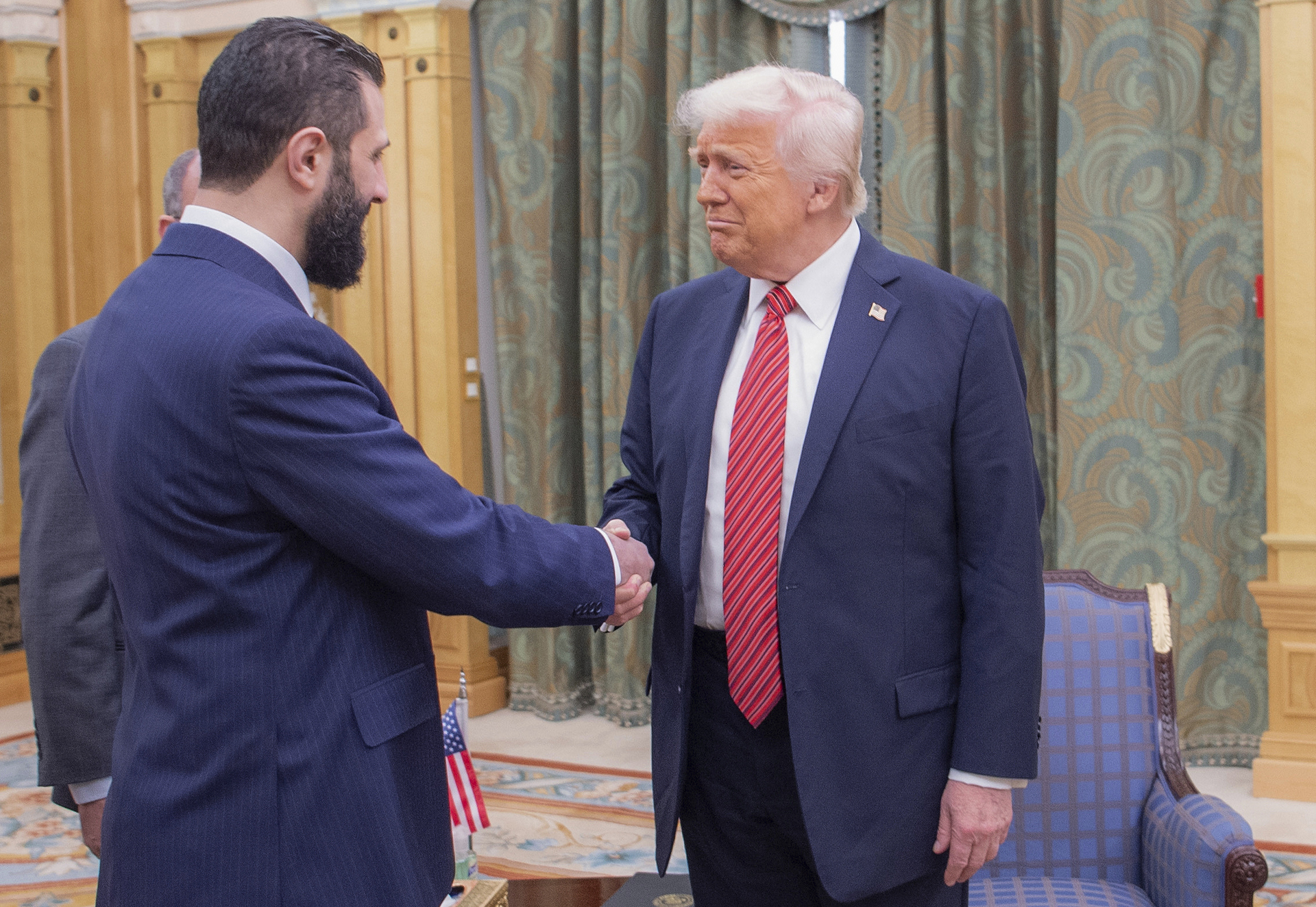 In this photo released by the Saudi Royal Palace, President Donald Trump, right, shakes hands with Syria's interim President Ahmad al-Sharaa, in Riyadh, Saudi Arabia, Wednesday, May 14, 2025. (Bandar Aljaloud/Saudi Royal Palace via AP)