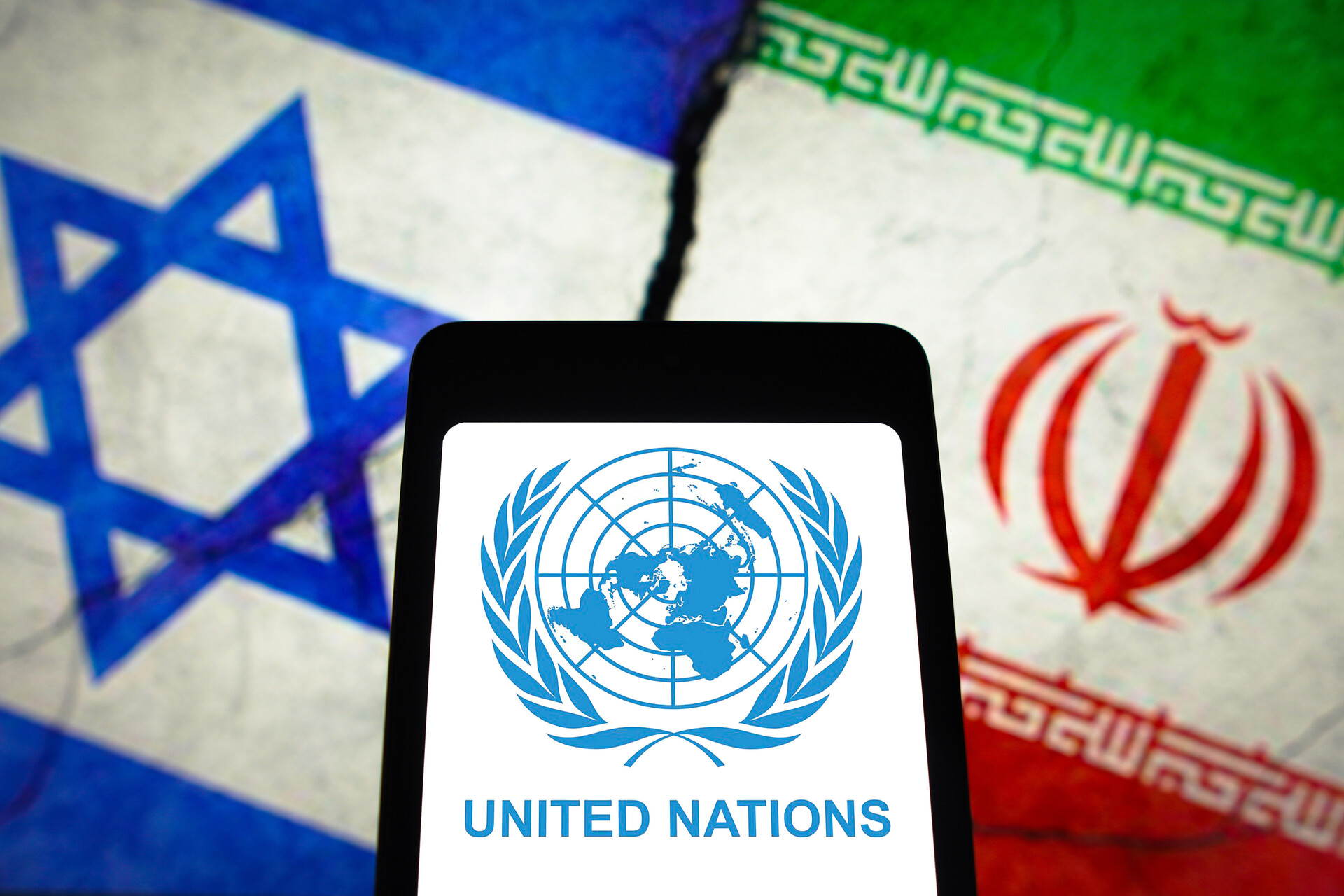 14/04/2024 April 14, 2024, Brazil: In this photo illustration, the United Nations (UN) logo is displayed on a smartphone screen and flags of Israel and Iran in the background. POLITICA Europa Press/Contacto/Rafael Henrique