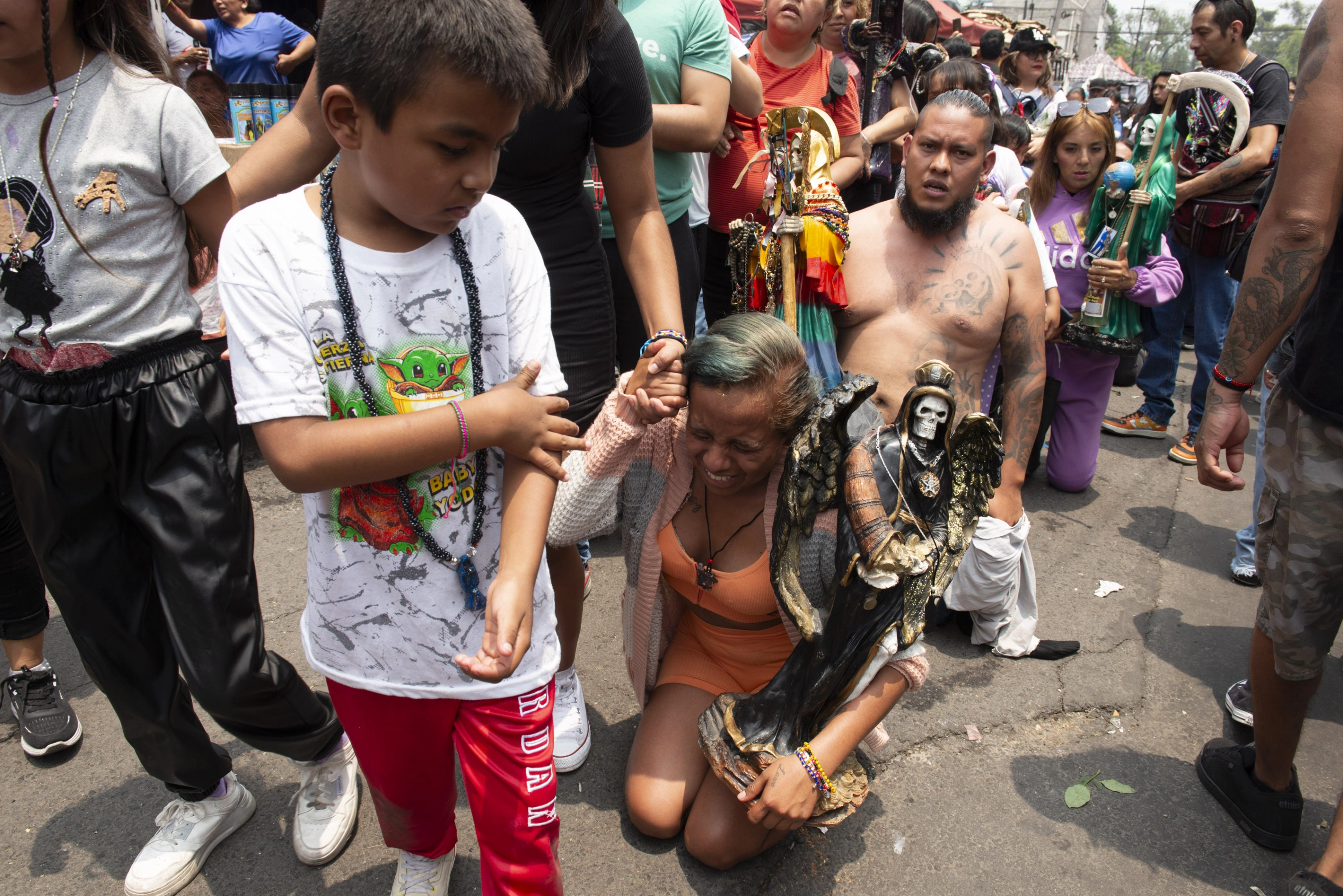 Una mujer, arrodillada ante la Santa Muerte.