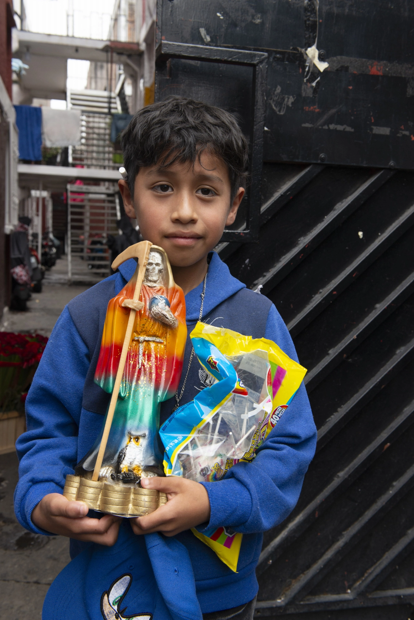 Un niño sostiene una figura que representa a la Santa Muerte.