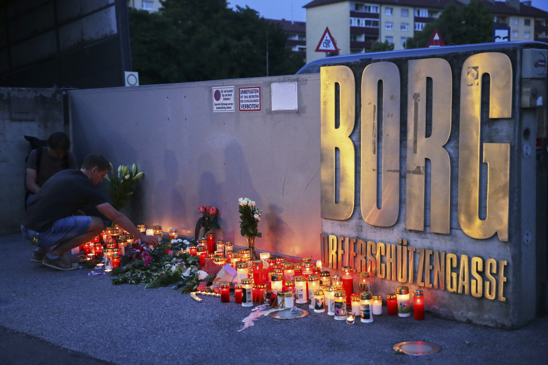 A man places a candle at the entrance to a school after a deadly shooting took place there, in Graz, Austria, Tuesday, June 10, 2025. (AP Photo/Heinz-Peter Bader)