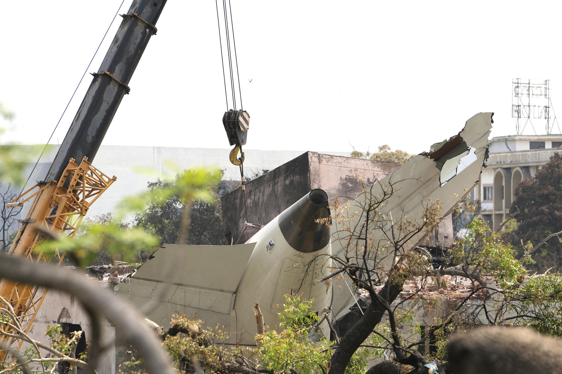 A crane lifts the tail of the Air India plane, which crashed on Thursday, from the roof of a building in Ahmedabad, India, Saturday, June 14, 2025. (AP Photo/Ajit Solanki)