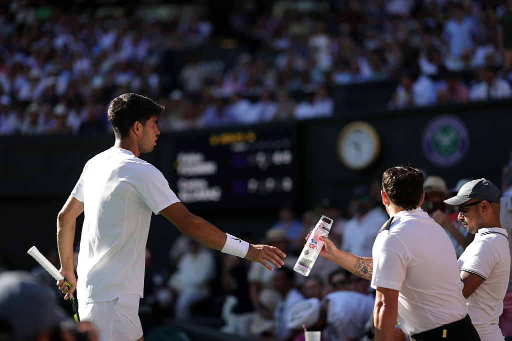 Alcaraj fornece uma garrafa de água para servir a mulher que viajou em Wimbledon.