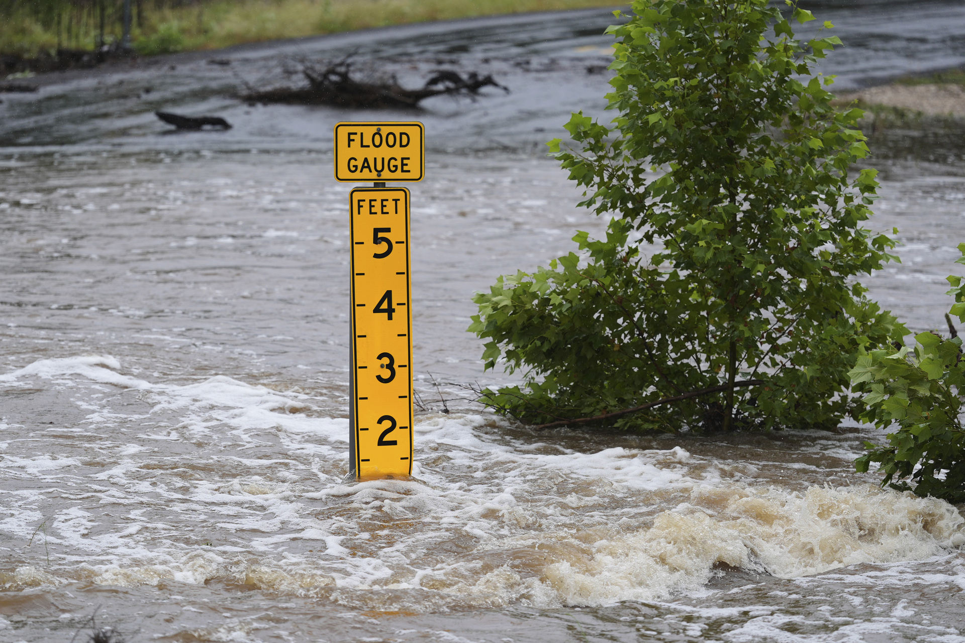A flood gauge marks the height of water flowing over a farm-to-market road near Kerrville, Texas, on Friday, July 4, 2025. (AP Photo/Eric Gay)
