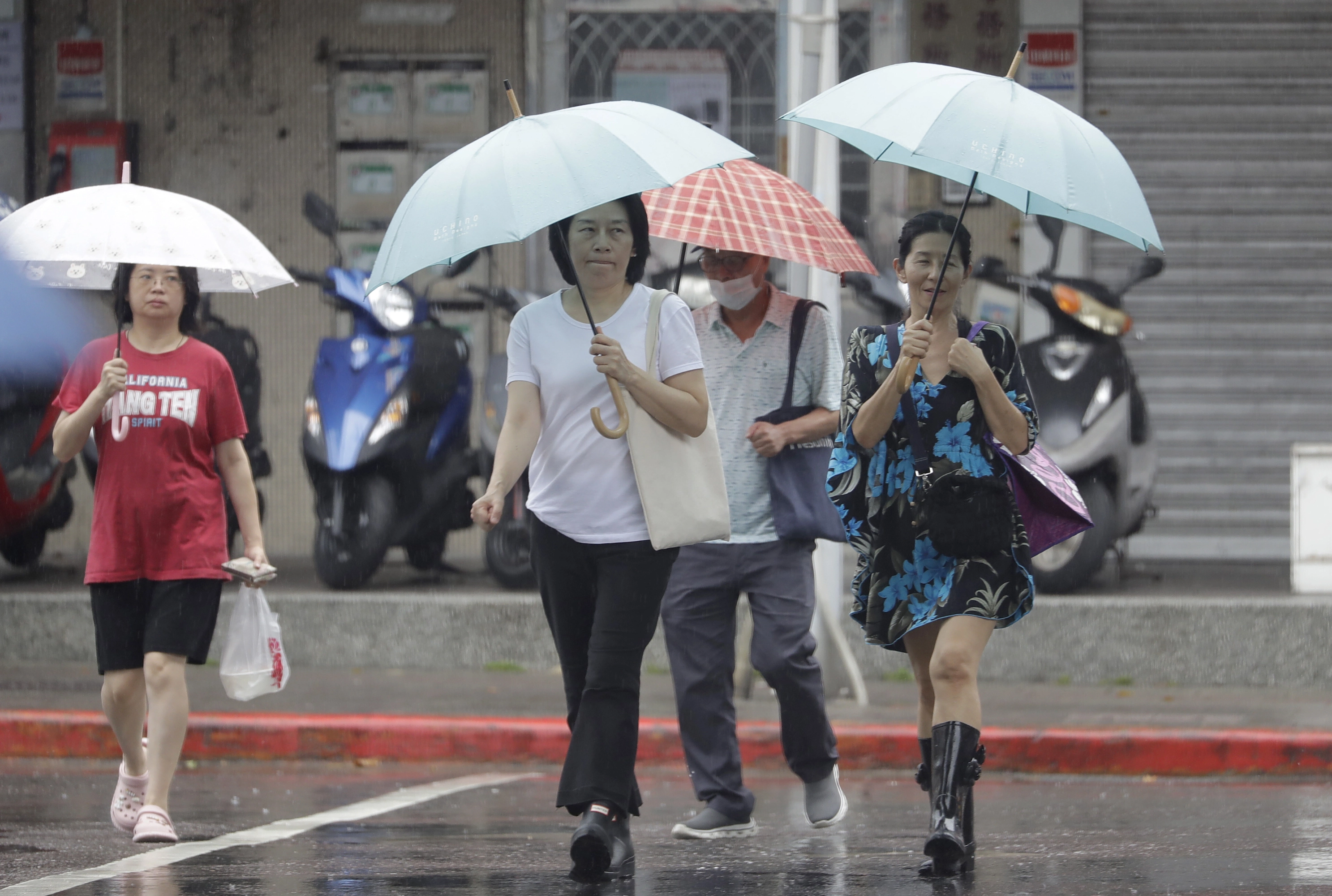 Varias personas caminan bajo la lluvia en Taipei, Taiwán, el lunes 7 de julio de 2025, durante el paso del tifón Danas por Taiwán.