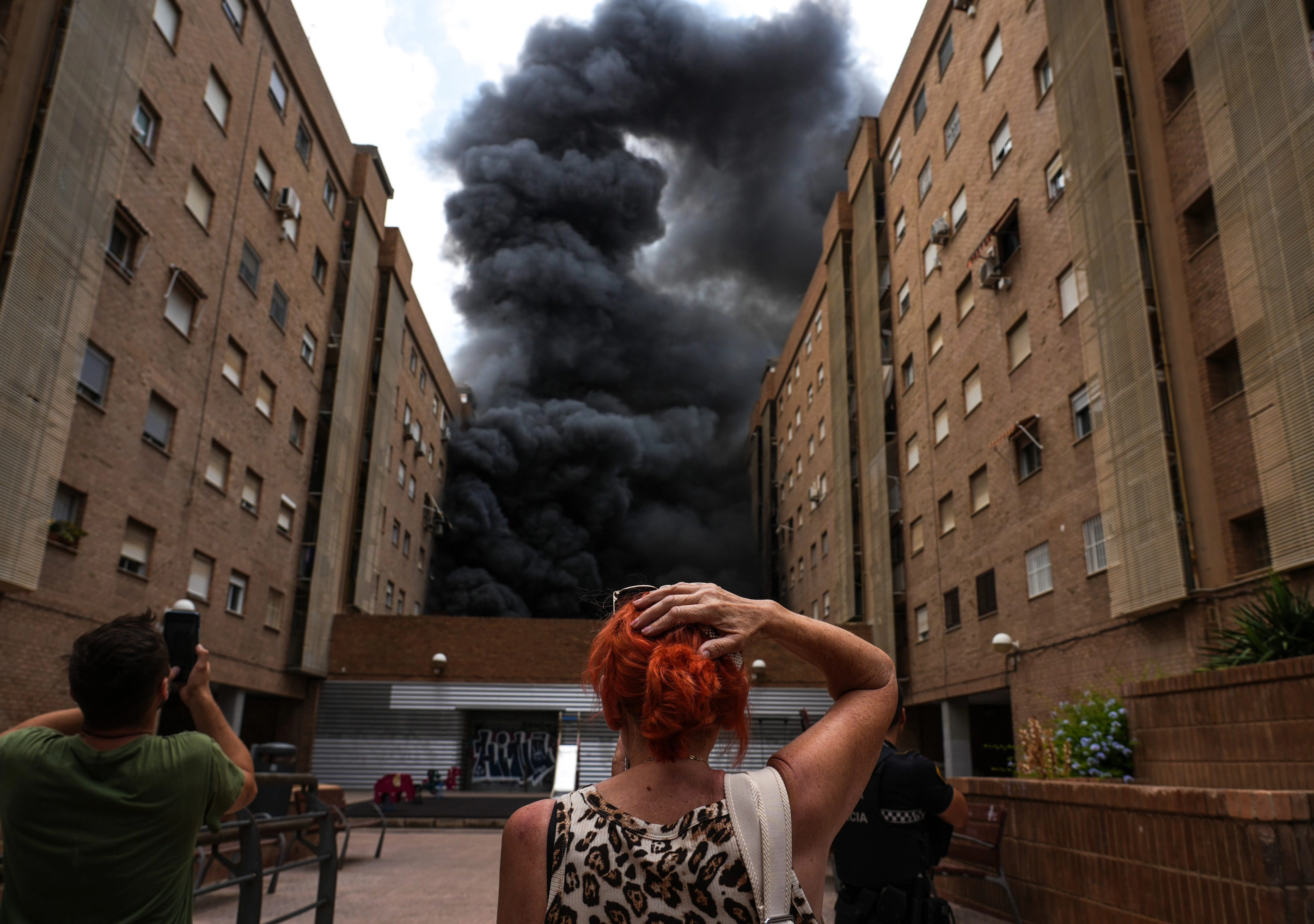 Vecinos observan la intensa columna de humo durante un incendio en la avenida del Puerto de Valencia.