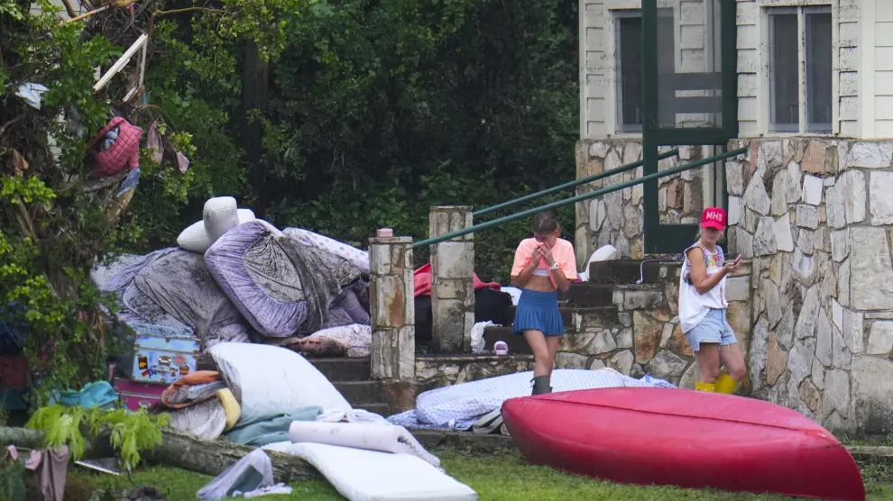 Dos mujeres observan las pertenencias, afuera de los dormitorios en Camp Mystic, cerca de la orilla del río Guadalupe después de que la riada.