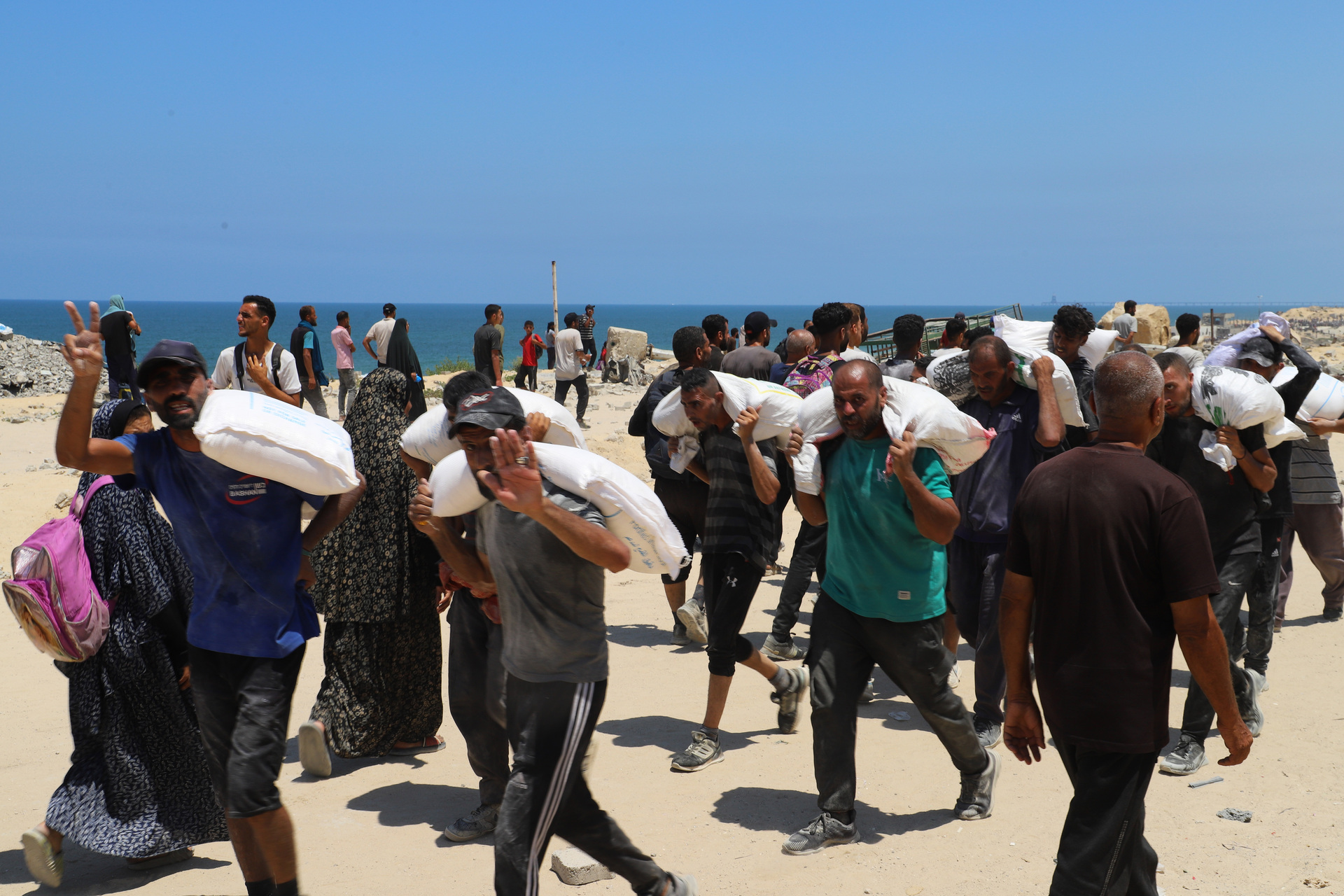 July 22, 2025, Gaza, Gaza Strip, Palestinian Territory: People make their way along al-Rashid street in western Jabalia on July 22, 2025, towards trucks carrying humanitarian aid after they entered the northern Gaza Strip through the Israeli-controlled Zikim border crossing. The head of Gaza's largest hospital on June 22, said 21 children have died due to malnutrition and starvation in the Palestinian territory in the past three days, while Israel pressed a devastating assault (Credit Image: © Abdullah Abu Al-Khair/APA Images via ZUMA Press Wire)