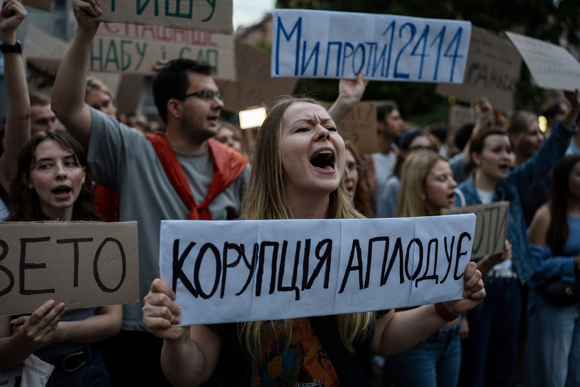A woman chants while holding a banner that reads, “Corruption Applauds,” during a protest against a law targeting anti-corruption institutions in central Kyiv, Ukraine, Tuesday, July 22, 2025. (AP Photo/Alex Babenko)